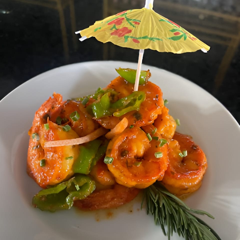 Hazel's Jamaican jerk shrimp with green peppers, garnished with a cocktail umbrella and rosemary.