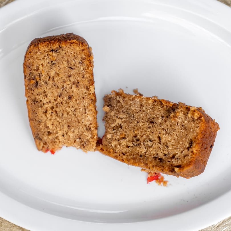 Two slices of Jamaican rum cake with red fruit pieces on a white plate.